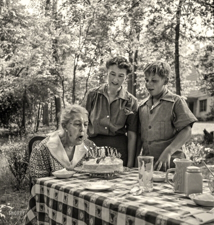 Photo showing: Grandma Taylor -- June 1942. Greenbelt, Maryland. Grandma Taylor blows out the candles on her 83rd birthday cake.
