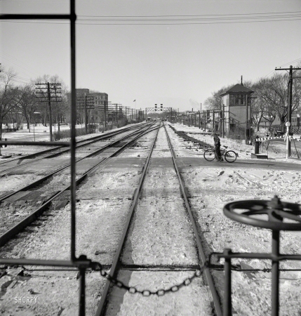 Photo showing: Bicycle Crossing -- January 1943. Freight train rushing through the town of Elmhurst, Illinois.