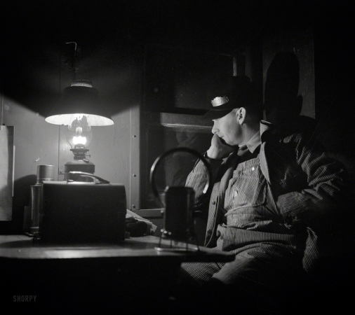 Photo showing: Lux Aeterna -- March 1943. Brakeman Jack Torbet at the window of the caboose
pulling out of Waynoka, Oklahoma, on the Atchison, Topeka & Santa Fe. 