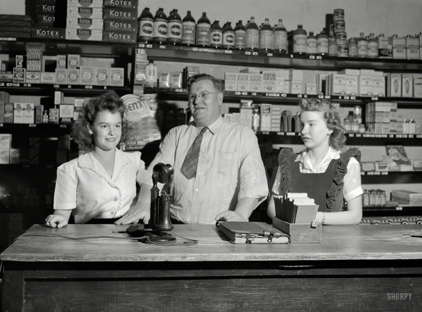 Photo showing: Family Business -- April 1943. San Augustine, Texas. Clyde Smith, grocer, with his two daughters.