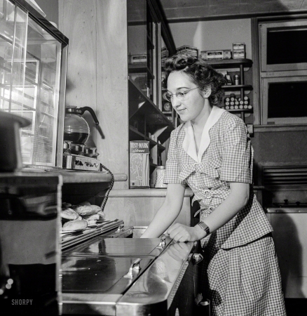 Photo showing: Gingham Style -- June 1943. Arlington, Virginia. Girl getting food in the service shop at Idaho Hall, Arlington Farms.
