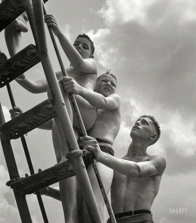 Photo showing: The Ascent of Man -- July 1943. Montgomery County, Maryland. Climbing the ladder to the sliding board at the Glen Echo swimming pool.