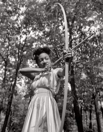 Photo showing: I Shot an Arrow -- -- August 1943. Bear Mountain, New York. Loretta Gyles
of the Methodist Camp Service pulling a bow at Camp Fern Rock.