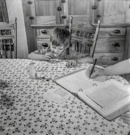 Photo showing: Hard Licker -- July 1942. East Montpelier, Vermont. Richard, age 5, son of the farmer Charles Ormsbee,
has his own war project -- he has agreed to lick all the savings stamps for the family.