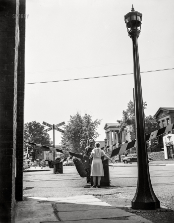 Photo showing: Stop, Look and Listen -- June 1943. New Britain, Connecticut. A woman railroad crossing watcher letting down the gates until the train passes.