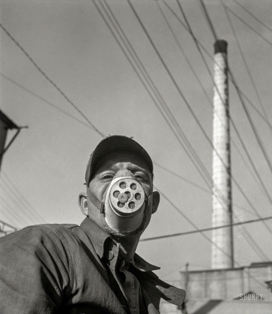 Photo showing: Eagle-Picher -- January 1943. The operator of a zinc ore loader at the Eagle-Picher smelting
plant near Cardin, Oklahoma, is protected against harmful dust by a mask.