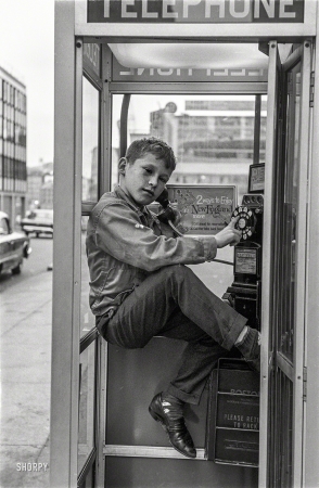 Photo showing: Where Im Calling From -- Boy in telephone booth, Boston, 1963.