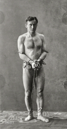 Photo showing: The Great Escapist -- Circa 1900. Harry Houdini (1874-1926), full-length portrait, standing, in chains.