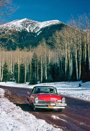 Photo showing: Red, White, Blue -- January 1963. Lincoln convertible on snow road.