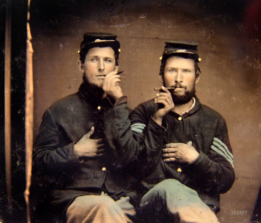 Photo showing: Second-Hand Smoke -- 1861-65. Two unidentified soldiers in Union uniforms holding cigars in each other's mouths.