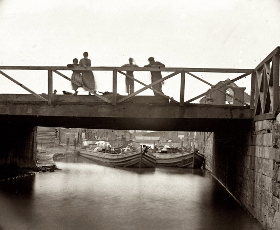 Photo showing: A Distant Crossing -- Spring 1865. Richmond, Virginia. Canal Bridge at foot of Seventh Street after fall of the city.