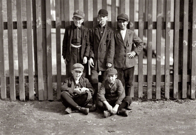 Photo showing: Work History -- October 1911. Lowell, Mass. Standing: Michael Keefe, 32 Marion St., been at work in No. 1 mule room, Merrimac Mill, eight months. Apparently 13 years old. John Risheck, 391 Adams St.; Cornelius Hurley, 298 Adams St., been at work in No. 1 mule room in Merrimac Mill for six months. About 13 or 14 probably. Sitting: John Neary, 211 Lakeview Ave.; smallest is Robert Magee, 270 Suffolk St. Apparently 12 years old. Been working in Mule Room No. 1, Merrimac Mill, one year.