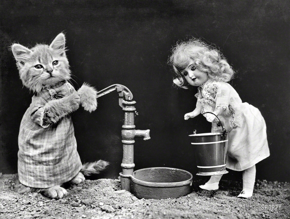 Photo showing: I Could Use a Drink -- 1914. Kitten in costume grasping pump handle, ready to fill water bucket carried by doll.