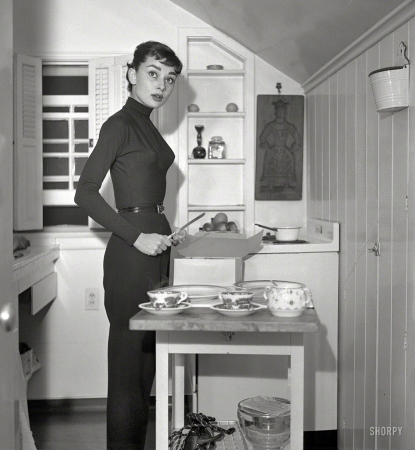 Photo showing: Piece of Cake -- Circa 1953, Actress Audrey Hepburn at home preparing and serving coffee and cake.