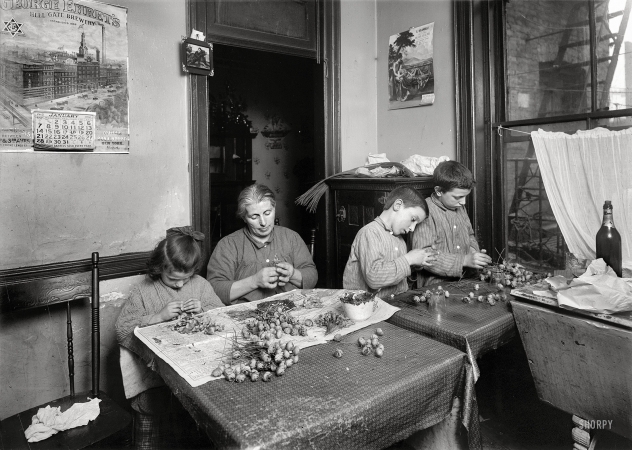 Photo showing: Carmine Street Tenement -- January 1912. New York. Basso family, 2 Carmine Street, Apt 17. Making roses in dirty, poorly lighted kitchen.