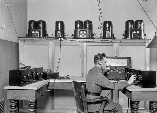 Photo showing: The Twiddler -- Washington, D.C., 1924. Tweaking the dials on a Freed Eisemann Neutrodyne receiver
and a Western Electric 138 amplifier. On the shelf: Westinghouse Rectigon battery chargers. 