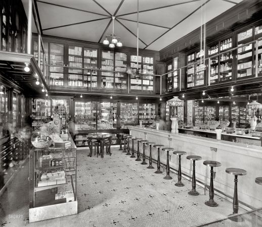 Photo showing: Ghost Jerk -- Circa 1909. Bertram Bros. drug store -- Detroit City Gas Co. light fixtures. Also a soda fountain and spectral clerk.