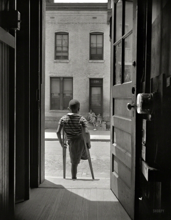 Photo showing: Danger City -- June 1942. Washington, D.C. Young boy standing in the doorway of his home on Seaton Road.
His leg was cut off by a streetcar while he was playing in the street.