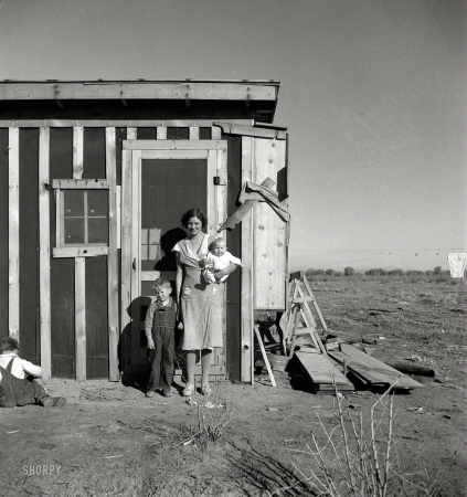 Photo showing: Four From Taos -- December 1935. Resettled at Bosque Farms project. Family of four from Taos Junction shows temporary dwelling.