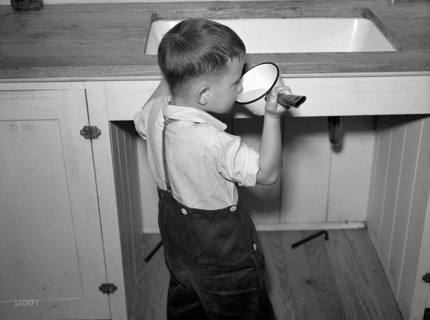 Photo showing: A Drink at the Sink -- May 1938. John Pope, son of farmer, at Irwinville Farms, Georgia.