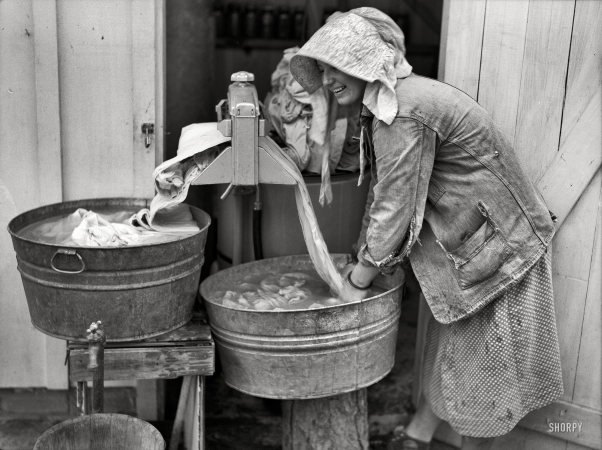Photo showing: Through the Wringer -- May 1938. Irwinville Farms, Georgia. Mrs. Coleman doing a washing.