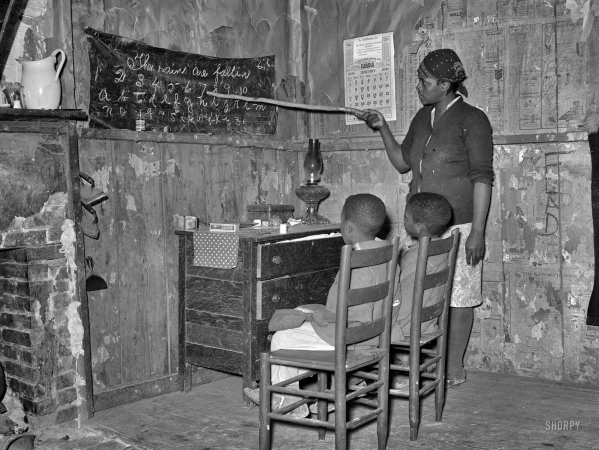 Photo showing: Transylvania Homeschool -- January 1939. Negro sharecropper mother teaching children numbers and alphabet in home. Transylvania, Louisiana.