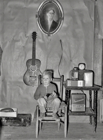 Photo showing: Young Gun -- January 1939. Sunflower Plantation. Son of tenant farmer in corner of living room. Pace, Mississippi.