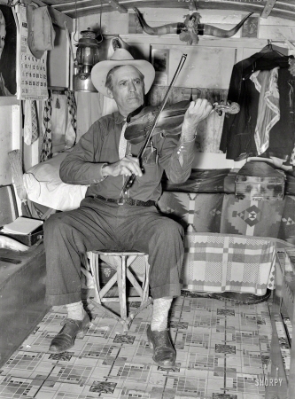 Photo showing: Fiddling With Mr. Bias -- February 1939. Mr. Bias, former cowboy, now travels around the country in a trailer. Has private income. Weslaco, Texas.