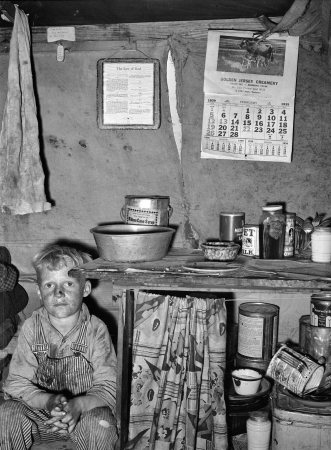 Photo showing: The Law of God -- February 1939. Child of migrant sitting by kitchen cabinet in tent home near Edinburg, Texas.