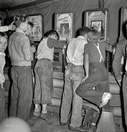 Photo showing: Short Subjects -- September 1938. 'It's a dirty gyp,' say the mine workers' sons in the penny arcade at outdoor carnival. Granville, West Virginia.