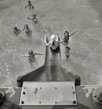 Photo showing: Slippery Characters: 1942 -- May 1942. Greenbelt, Maryland. A constant stream of water runs down the swimming pool slide.