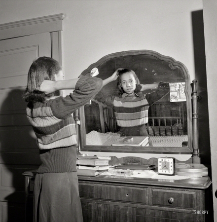 Photo showing: Mirror, Mirror -- February 1942. Detroit, Michigan. Negro girl putting up her hair.
