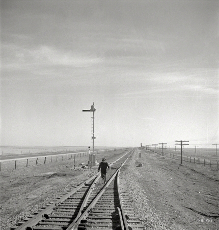 Photo showing: A Fork in the Railroad -- March 1943. Sumnerfield, Texas. Brakeman running back to his train
on the Atchison, Topeka & Santa Fe Railroad between Amarillo and Clovis.