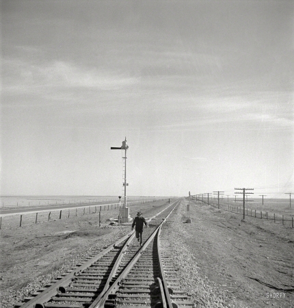 Photo showing: A Fork in the Railroad -- March 1943. Sumnerfield, Texas. Brakeman running back to his train
on the Atchison, Topeka & Santa Fe Railroad between Amarillo and Clovis.