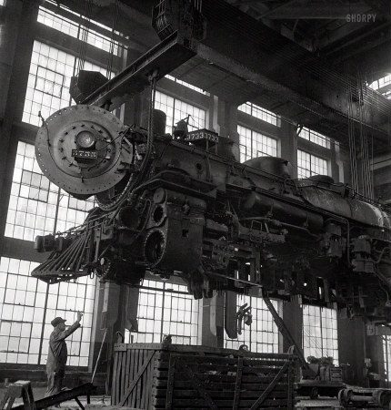 Photo showing: Iron Butterfly -- March 1943. Albuquerque, New Mexico. Lifting an engine to be carried to
another part of the Atchison, Topeka & Santa Fe shops for wheeling.