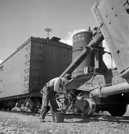 Photo showing: Brakeman Capsey -- March 1943. Acomita, New Mexico. Santa Fe brakeman R.E. Capsey repacking a journal box.