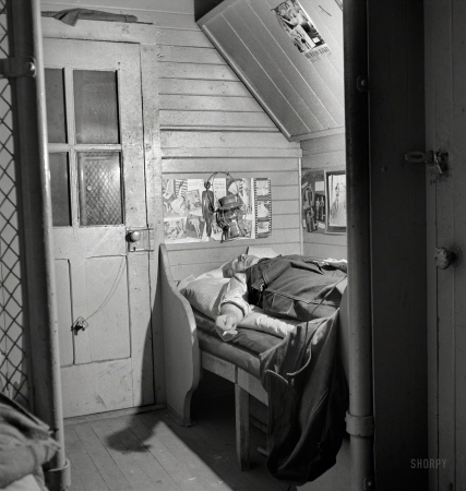 Photo showing: In the Caboose -- March 1943. Barstow, California. A brakeman on the Atchison, Topeka and Santa Fe Railroad resting in his caboose at night.