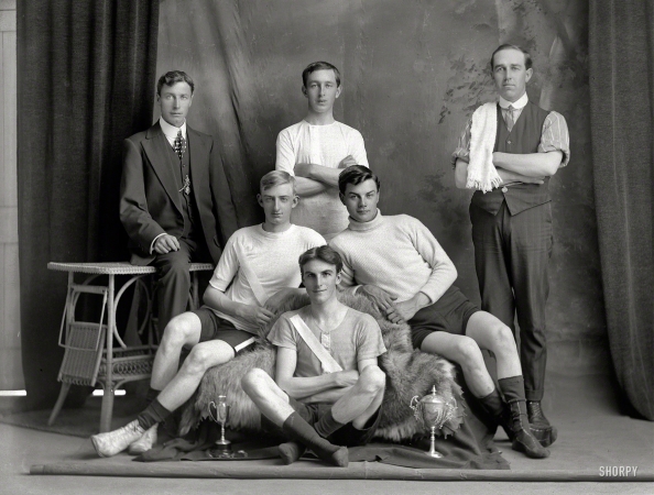 Photo showing: Minor Heroes -- New Zealand circa 1910. Bicycle road racing team with manager with polka dot tie and coach alongside, Christchurch.