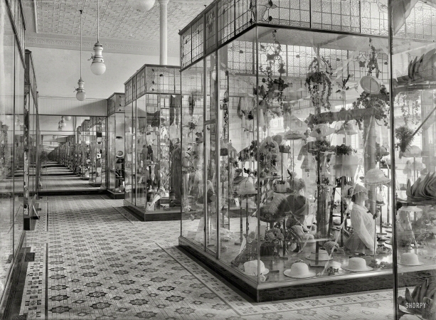 Photo showing: Hat-Mart -- New Zealand, 1915. Display cases in the Economic drapery store, Wanganui, containing hats, gloves, etc.