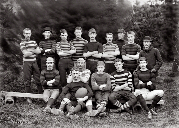 Photo showing: Rugged Ruggers -- Wellington, New Zealand, 1890. Post and Telegraph Department football team
with men in rugby kit. Postmaster William Copeland behind man with ball. 