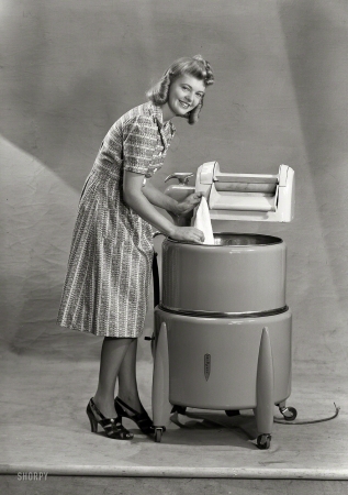Photo showing: Princess Unplugged -- New Zealand circa 1950s. Model with wringer washing machine.
