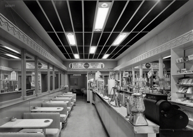 Photo showing: Try Our Golden Crumpets -- 1950s. Wellington, New Zealand. Interior of Sunshine Milk Bar.
